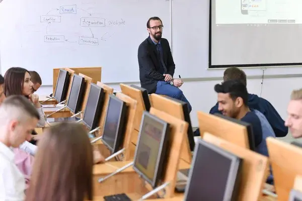 estudiantes usando computadoras en clase con su profesor